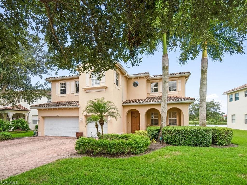 a view of a house with a small yard and a large tree