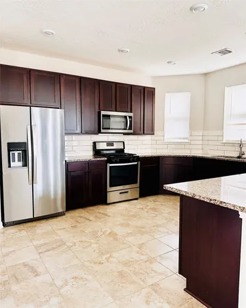 a kitchen with stainless steel appliances granite countertop a stove a refrigerator and a sink