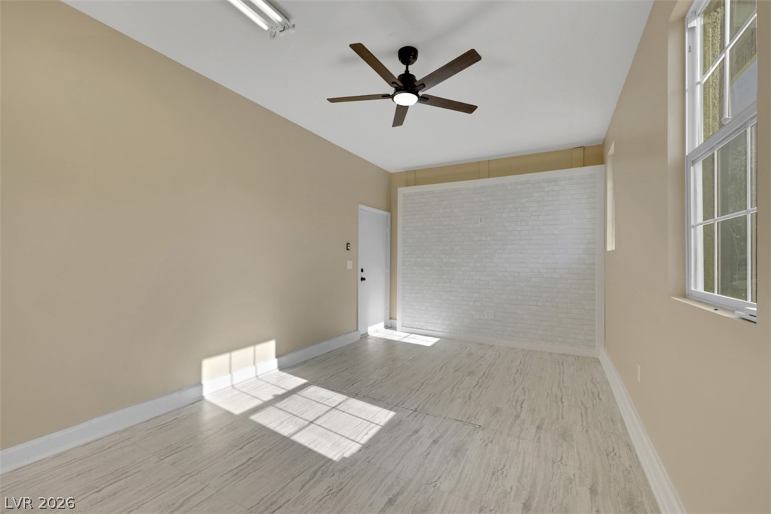 10328 Hawk Ravine Street Las Vegas, NV 89178 - Photo 52 of 55 A well-lit bonus room features a contemporary ceiling fan, white brick accent wall, and durable plank flooring.