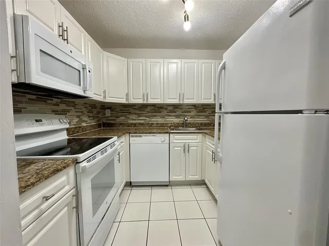 a kitchen with white cabinets and white appliances