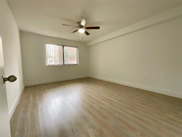 an empty room with wooden floor fan and windows