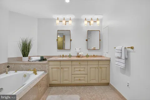 a spacious bathroom with a granite countertop sink a large mirror and a bathtub