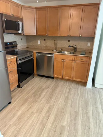 a kitchen with stainless steel appliances a sink a stove a microwave and cabinets