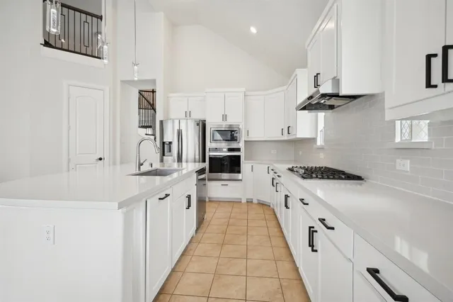 a large kitchen with stainless steel appliances granite countertop a lot of counter space and wooden floors