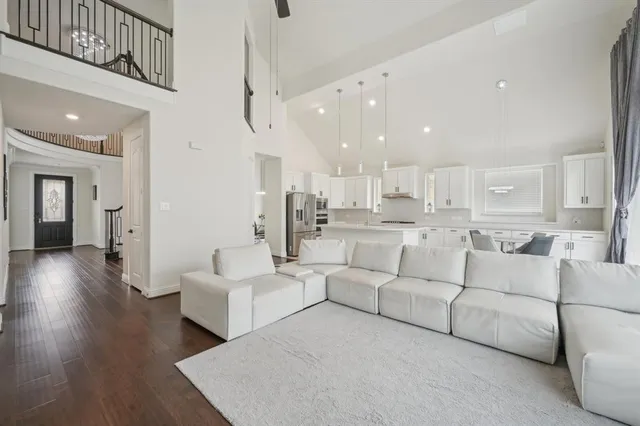 a living room with couches and kitchen view with wooden floor