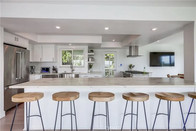 a kitchen with stainless steel appliances kitchen island granite countertop white cabinets and chairs