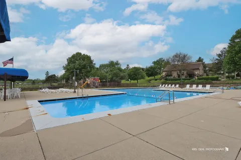 a view of swimming pool with outdoor seating and trees in the background