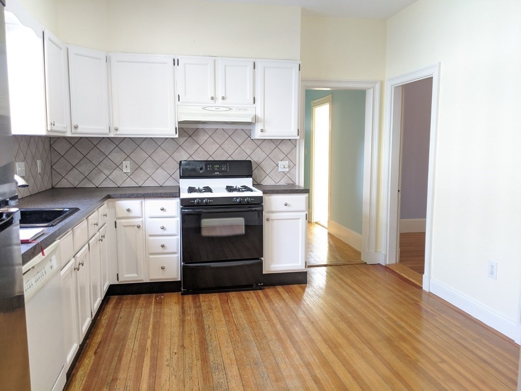 a kitchen with cabinets appliances and wooden floor