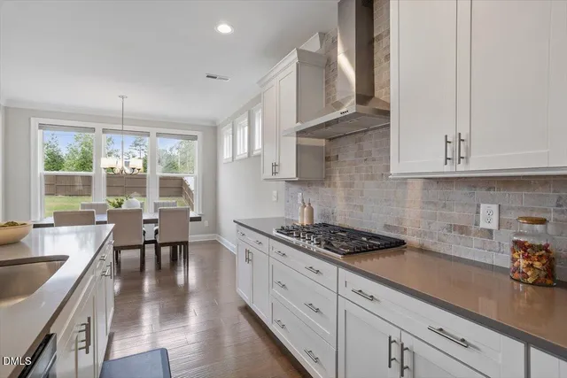 a kitchen with granite countertop a stove a sink a dining table and chairs