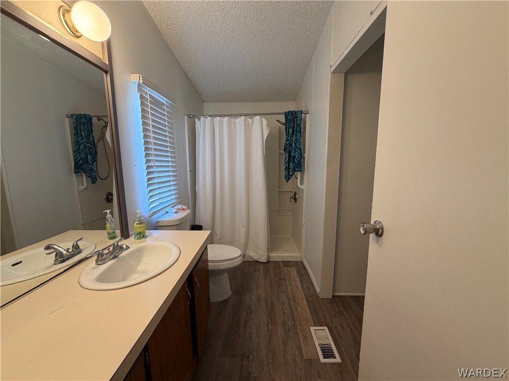 1910 Rio Grande Road Bullhead City, AZ 86442 - Photo 17 of 29 Bathroom featuring a single vanity with a laminate countertop and an integrated sink, wood-finish flooring, and a shower/tub combination with a white shower curtain