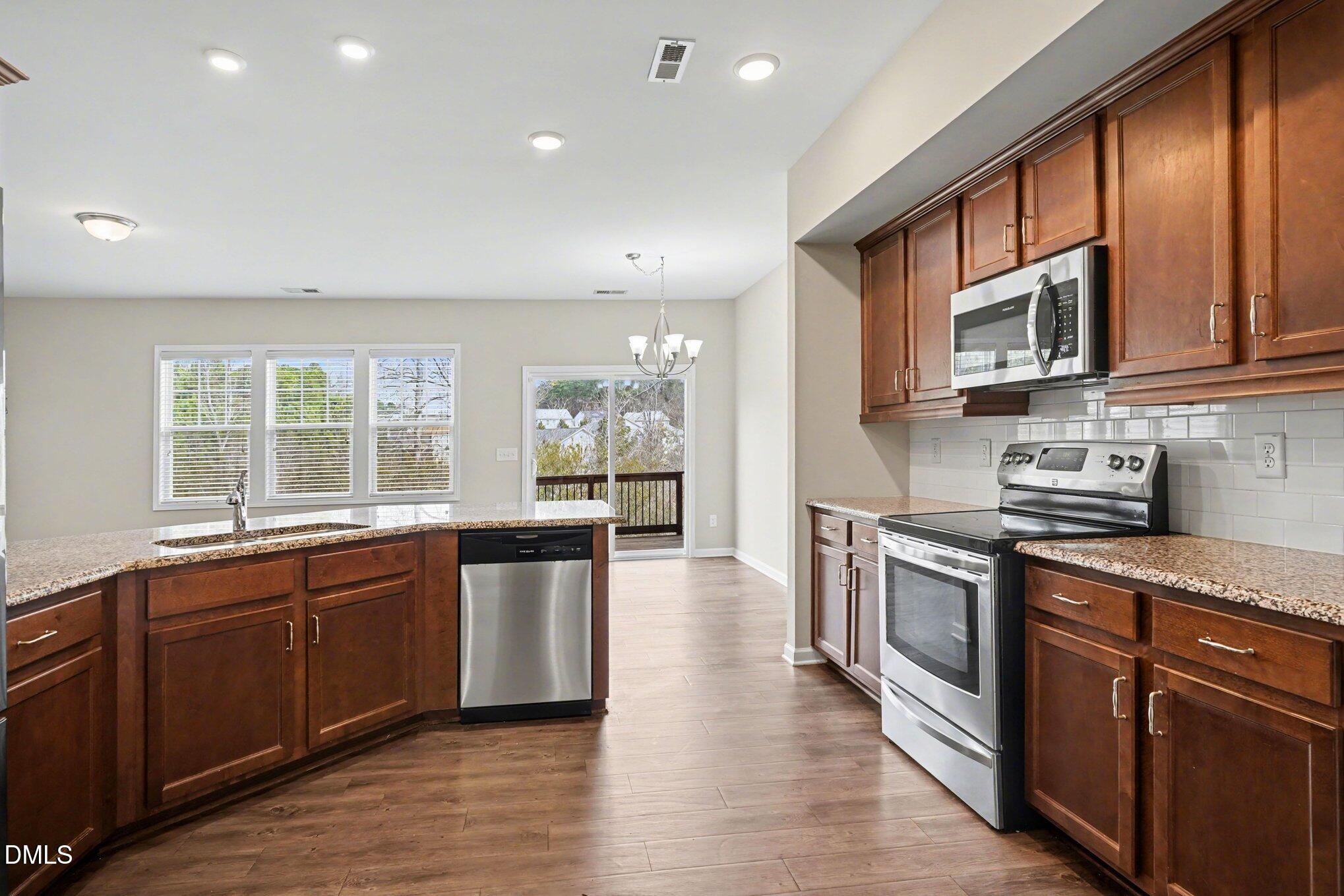 4245 Lofty Ridge Place Morrisville, NC 27560 - Photo 8 of 31 a large kitchen with stainless steel appliances granite countertop a stove a sink dishwasher and a microwave oven with wooden cabinets