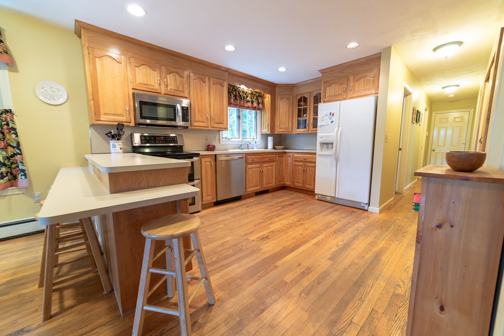 1565 West Street Wrentham, MA 02093 - Photo 9 of 30 a kitchen with stainless steel appliances granite countertop a refrigerator a stove top oven a sink dishwasher and white cabinets with wooden floor