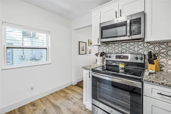 a kitchen with granite countertop cabinets stainless steel appliances and a window