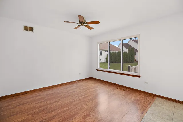 a view of empty room with wooden floor and fan