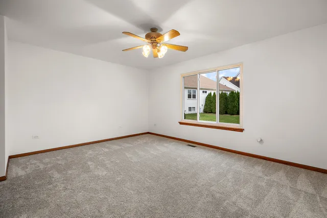 an empty room with windows and chandelier fan