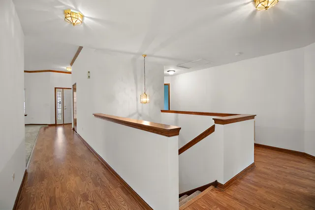 a hallway with stairs and wooden floor