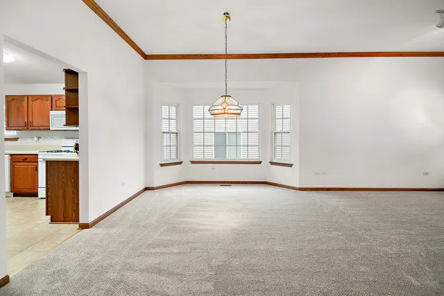 a view of an empty room with window and kitchen view