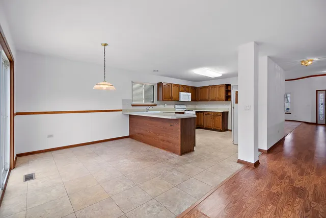 a view of a kitchen with a sink wooden cabinets and a living room