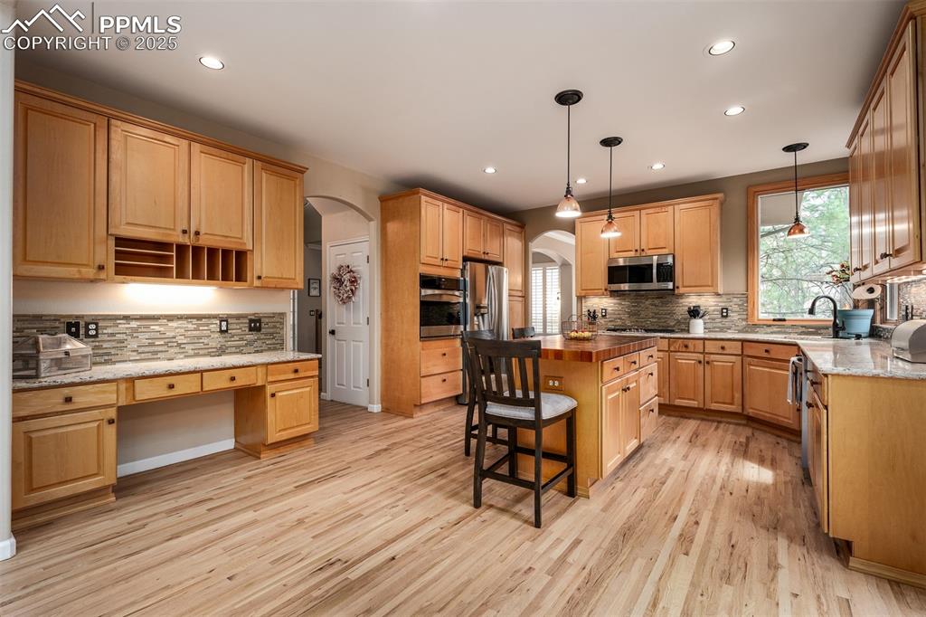15580 Deercross Court Colorado Springs, CO 80921 - Photo 16 of 50 a kitchen with stainless steel appliances kitchen island granite countertop a stove top oven a sink a dining table and chairs with wooden floor