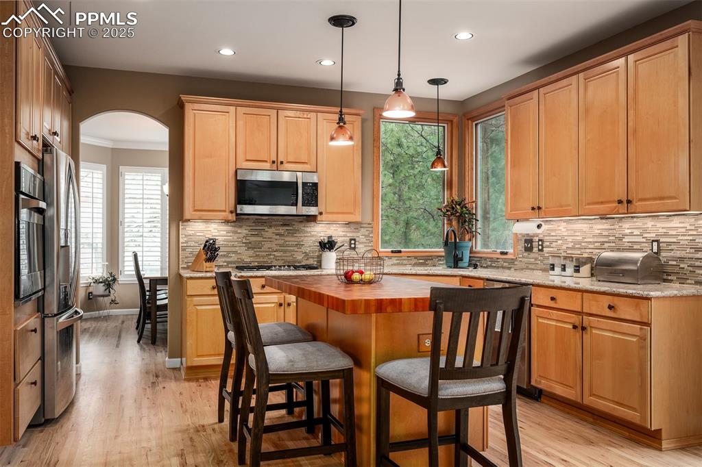 15580 Deercross Court Colorado Springs, CO 80921 - Photo 19 of 50 a kitchen with stainless steel appliances granite countertop a stove top oven a sink dishwasher a dining table and chairs with wooden floor