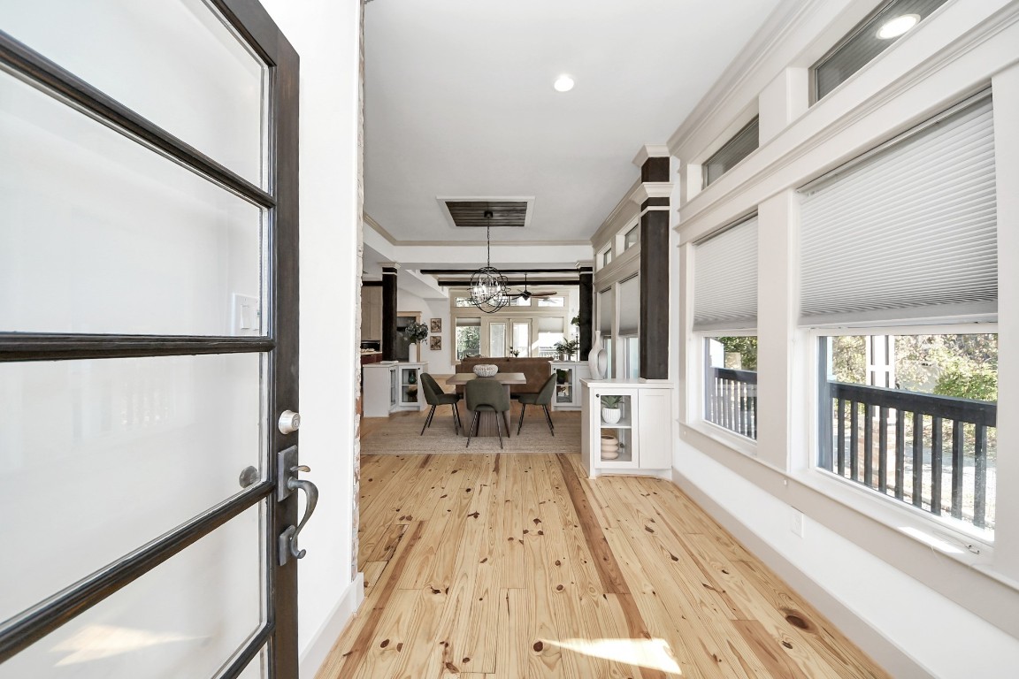 1202 Archer Street Houston, TX 77009 - Photo 21 of 47 This welcoming entryway is filled with natural light, highlighted by a sleek glass front door and light wood flooring. Large windows with tailored blinds brighten the space, creating an airy, open feel. The hallway seamlessly extends into a stylish dining area adorned with a modern chandelier and views of the outdoors, setting the perfect tone for a warm and inviting home.