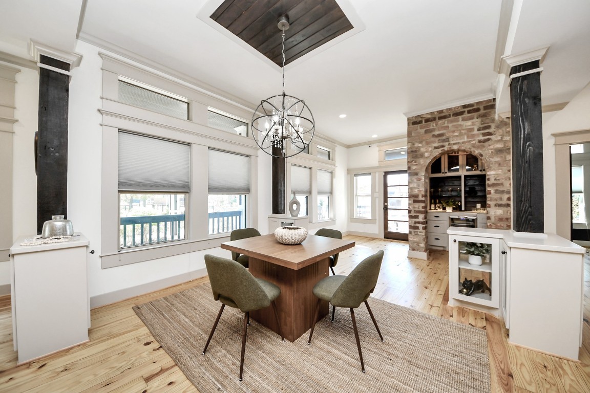 1202 Archer Street Houston, TX 77009 - Photo 23 of 47 This bright, modern dining area is framed by expansive windows and centered around a chic, contemporary chandelier. A striking architectural brick wall adds character and heritage craftsmanship to the space. The built-in bar area, complete with elegant wine storage and a luxurious white onyx stone countertop, enhances both functionality and refined design—perfect for intimate gatherings and effortless entertaining.