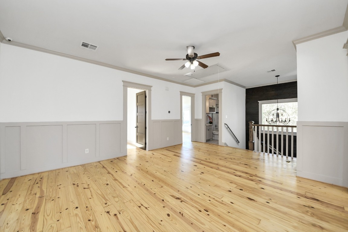 1202 Archer Street Houston, TX 77009 - Photo 29 of 47 This bright, spacious room boasts light hardwood floors, crisp white walls with elegant gray wainscoting, and a stylish ceiling fan. Its open layout offers views of a modern staircase and chandelier, while abundant natural light from large windows creates an inviting and airy atmosphere.