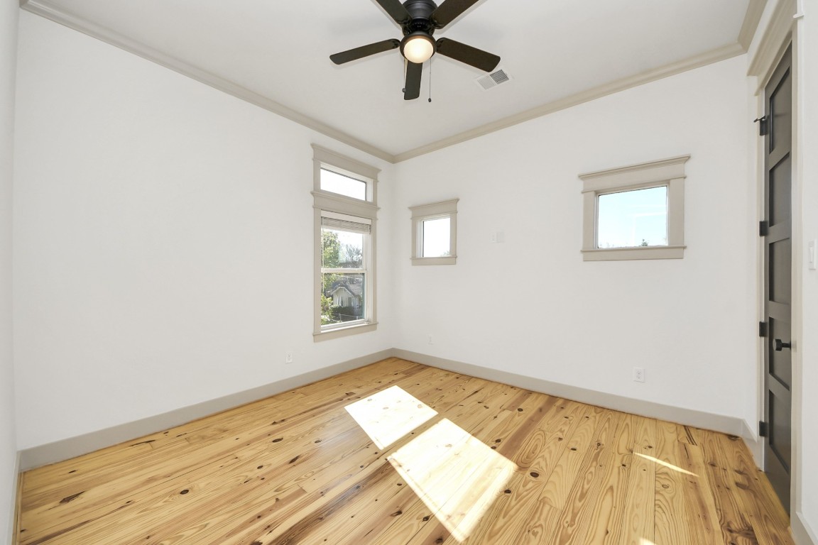 1202 Archer Street Houston, TX 77009 - Photo 35 of 47 This bright and airy room boasts natural wood flooring, neutral walls, and a ceiling fan. Three large windows fill the space with abundant sunlight, creating a warm and inviting atmosphere.
