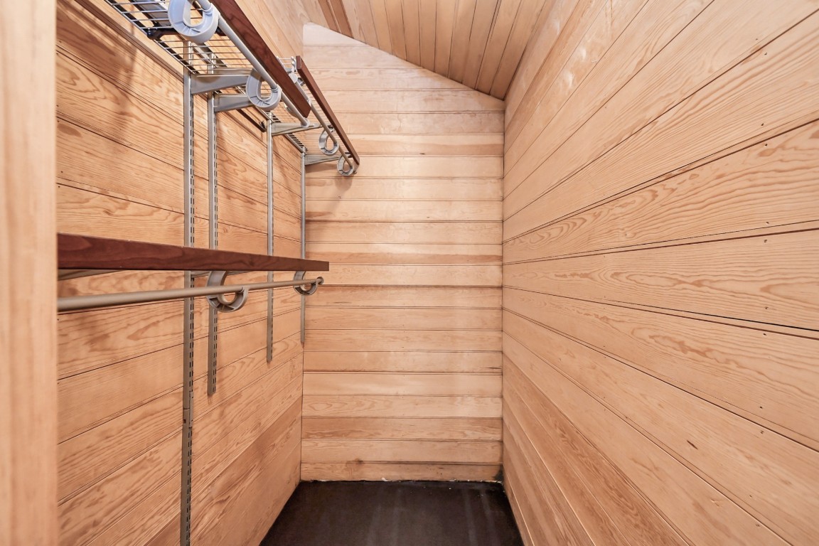 1202 Archer Street Houston, TX 77009 - Photo 41 of 47 This spacious walk-in closet features rich wooden walls and a soaring ceiling. Equipped with metal shelving and rods, it offers abundant storage while combining functionality with a refined, elegant aesthetic.