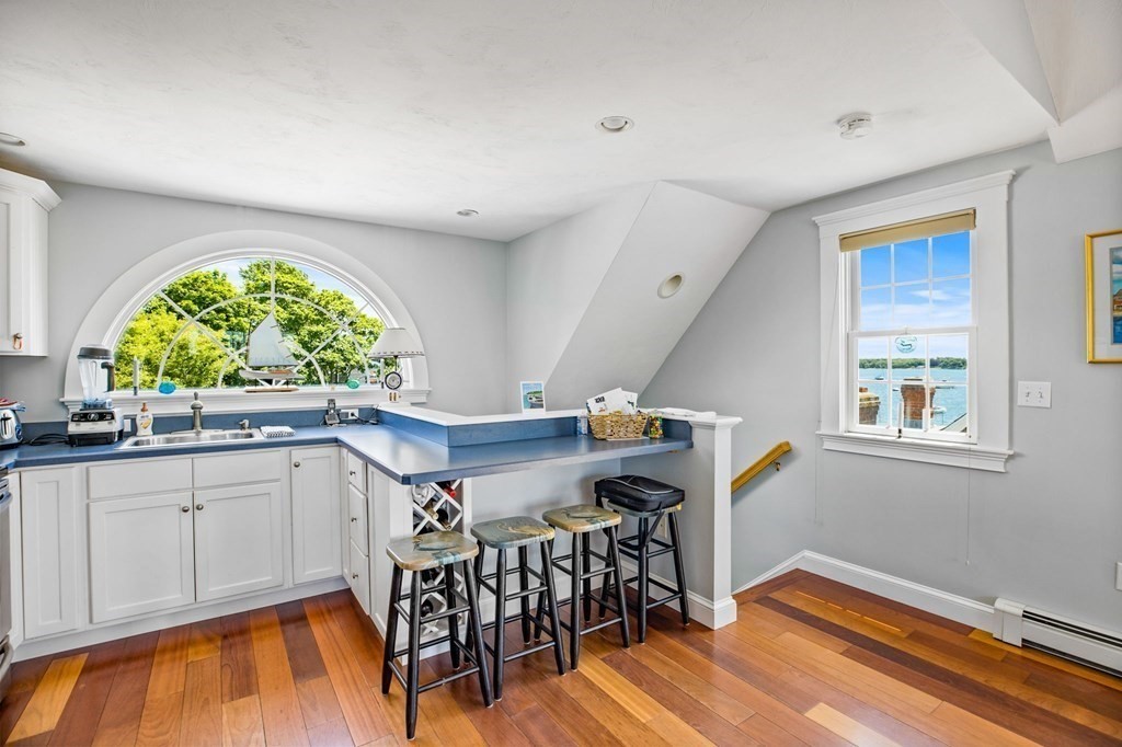 7 Pequod Lane Wareham, MA 02532 - Photo 20 of 26 a kitchen with granite countertop a stove a sink and white cabinets with wooden floor