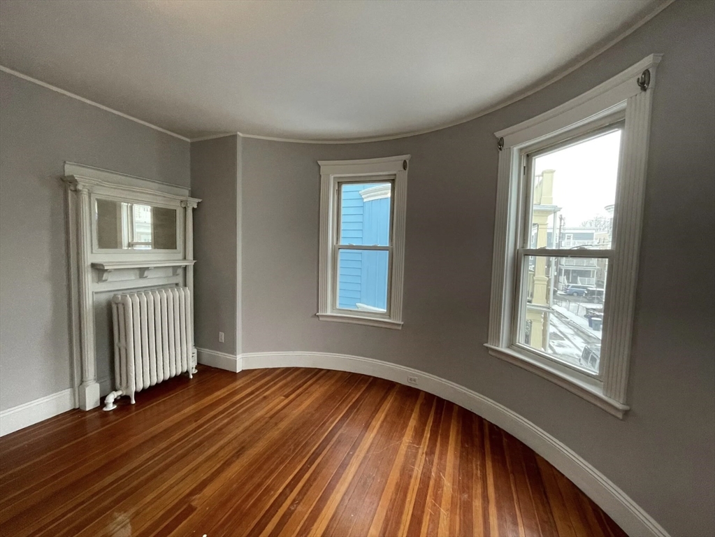 9 Sumner Square Boston, MA 02125 - Photo 9 of 10 a view of an empty room with wooden floor and a window