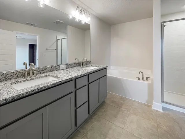 a bathroom with a granite countertop bathtub sink double vanity and mirror