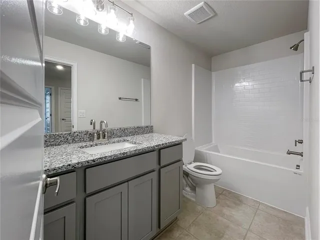 a bathroom with a granite countertop sink a toilet a mirror and bathtub