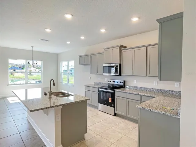 a kitchen with kitchen island granite countertop a sink counter top space appliances and cabinets