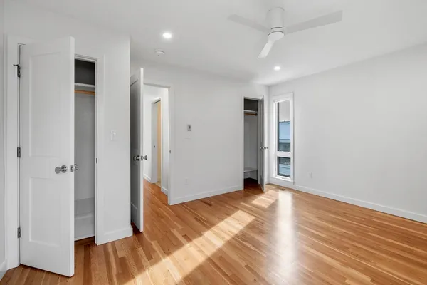 an empty room with wooden floor closet and windows