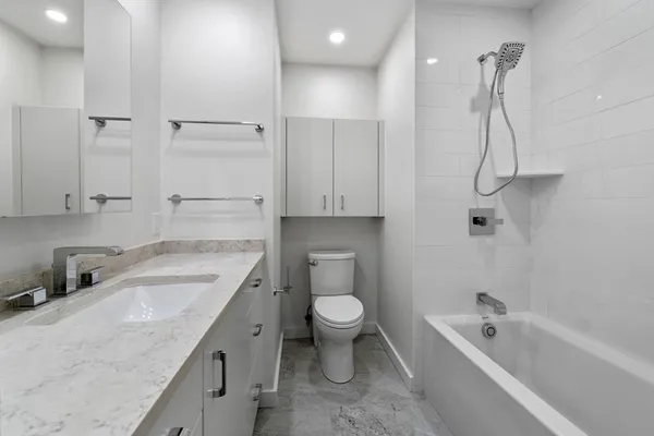 a bathroom with a granite countertop toilet sink and mirror