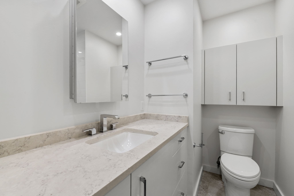 34 Constitution Way, Unit D Marblehead, MA 01945 - Photo 29 of 33 a bathroom with a granite countertop toilet sink and mirror