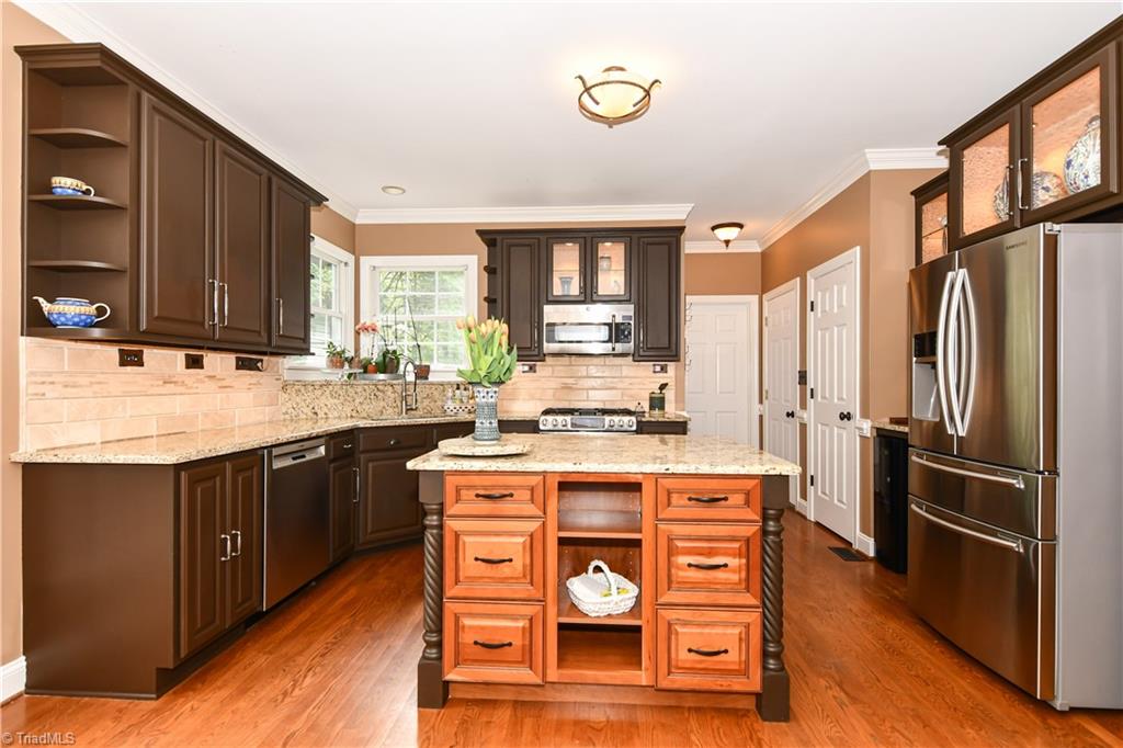 8305 Case Ridge Drive Oak Ridge, NC 27310 - Photo 17 of 48 Stunning kitchen with island workspace, granite, backsplash, SS apps, and custom work on cabinet displays and lighting.