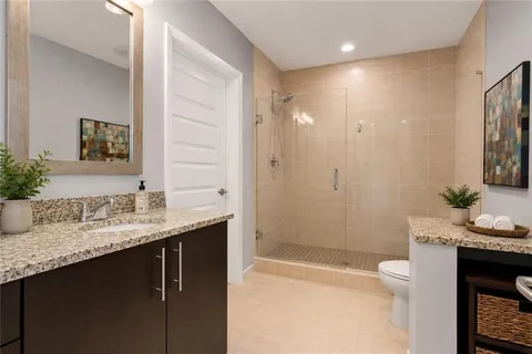 a bathroom with a granite countertop sink a toilet and shower