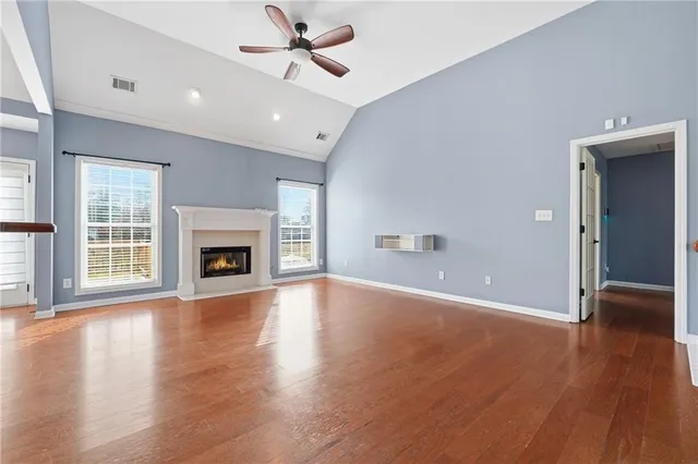 an empty room with wooden floor fireplace and windows