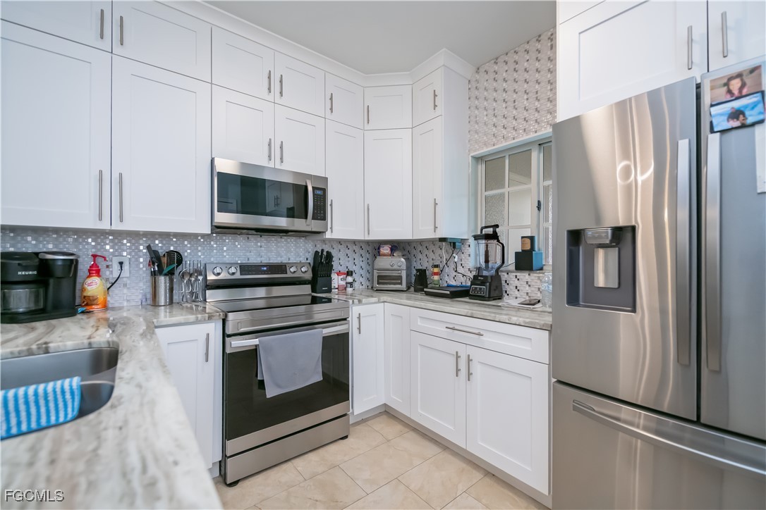 8513 Bernwood Cove Loop, Unit 212 Fort Myers, FL 33966 - Photo 11 of 43 a kitchen with stainless steel appliances granite countertop a stove a sink and a refrigerator