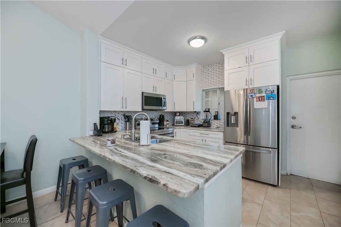 8513 Bernwood Cove Loop, Unit 212 Fort Myers, FL 33966 - Photo 9 of 43 a kitchen with kitchen island a refrigerator stove microwave and cabinets