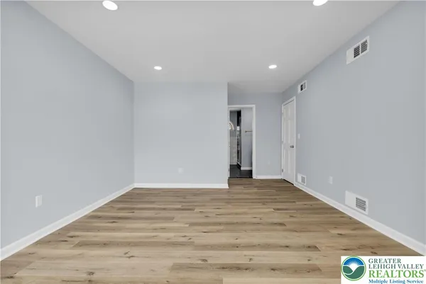 a view of a big room with wooden floor and windows