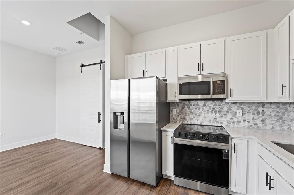 850 TETBURY Loop Oviedo, FL 32765 - Photo 2 of 24 a kitchen with stainless steel appliances white cabinets a stove a microwave and a refrigerator
