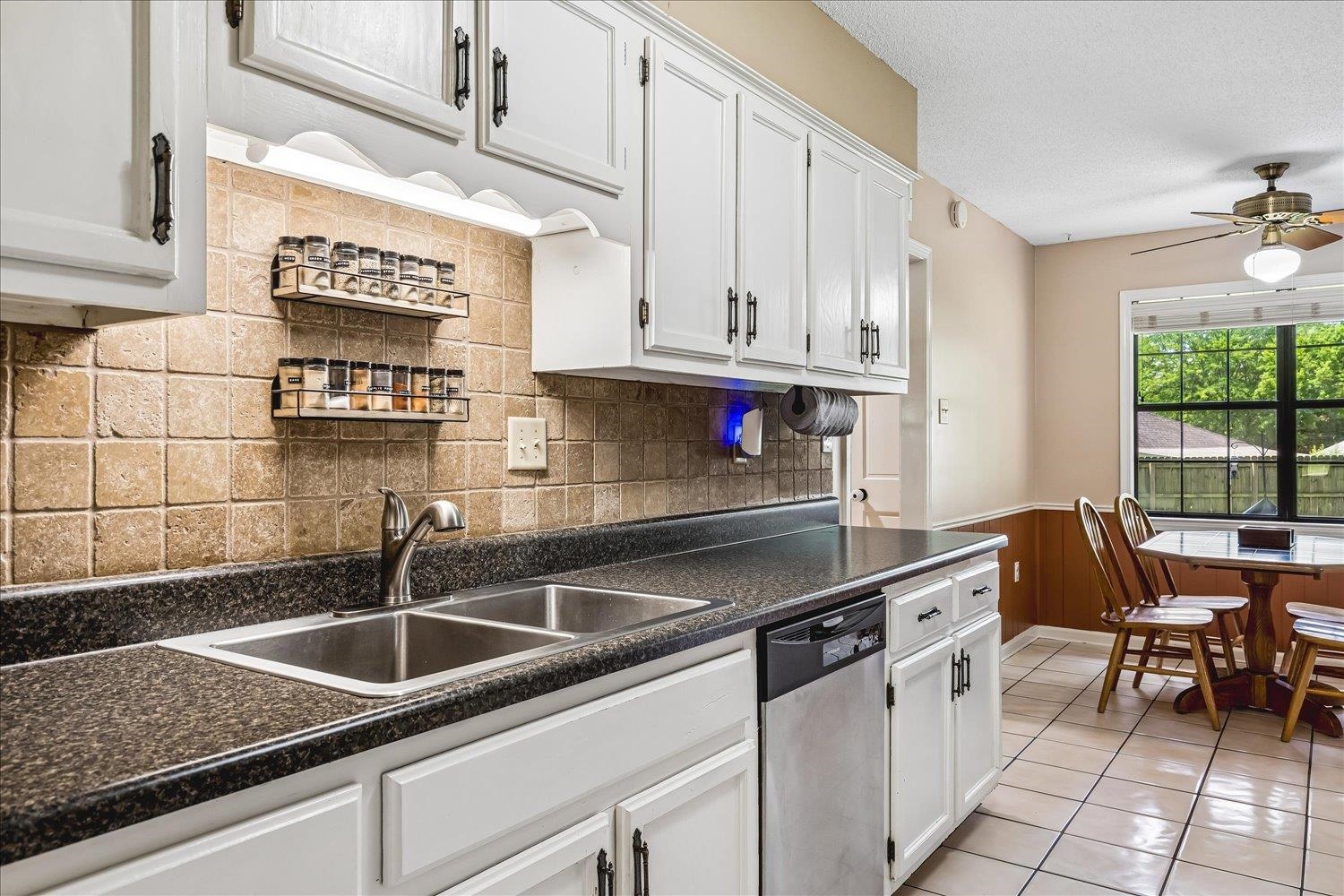 5711 Yale Road Bartlett, TN 38134 - Photo 7 of 29 Kitchen featuring white cabinetry, a double basin stainless steel sink, black speckled countertops, and a tiled backsplash