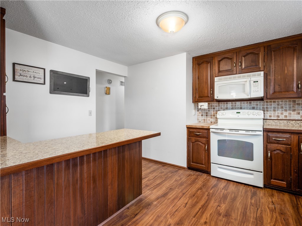12454 Old Rainer Road Roseville, OH 43777 - Photo 12 of 33 Kitchen featuring tasteful backsplash, dark hardwood / wood-style flooring, a textured ceiling, and white appliances