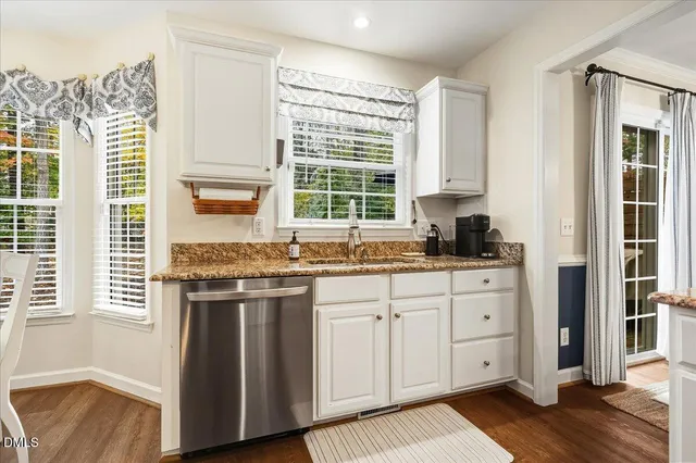 a kitchen with granite countertop a sink cabinets stainless steel appliances and a large window