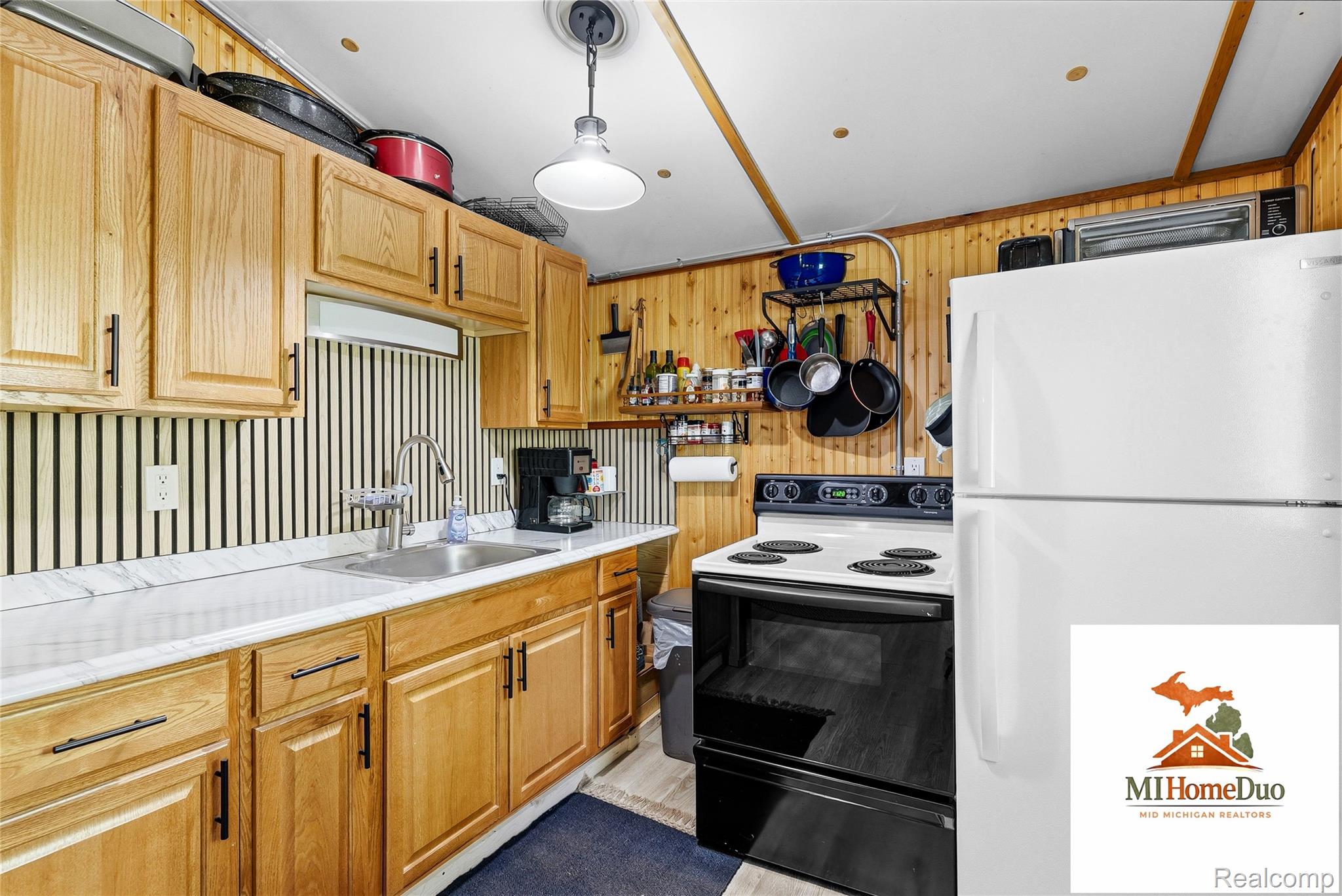 6960 Rumsay Street Harrison, MI 48625 - Photo 21 of 29 Functional kitchen featuring wood cabinetry, white countertops, a stainless steel sink, and a black and white electric range
