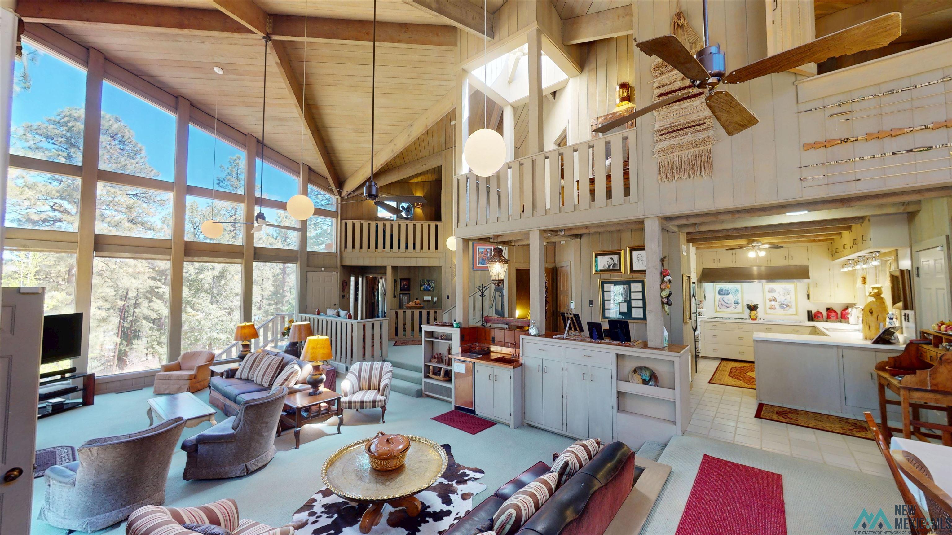 39 Alta Vista Rociada, NM 87742 - Photo 3 of 54 Great room featuring an open-concept design, soaring wood-paneled ceilings, a wall of expansive windows, and a multi-level layout with a lofted area