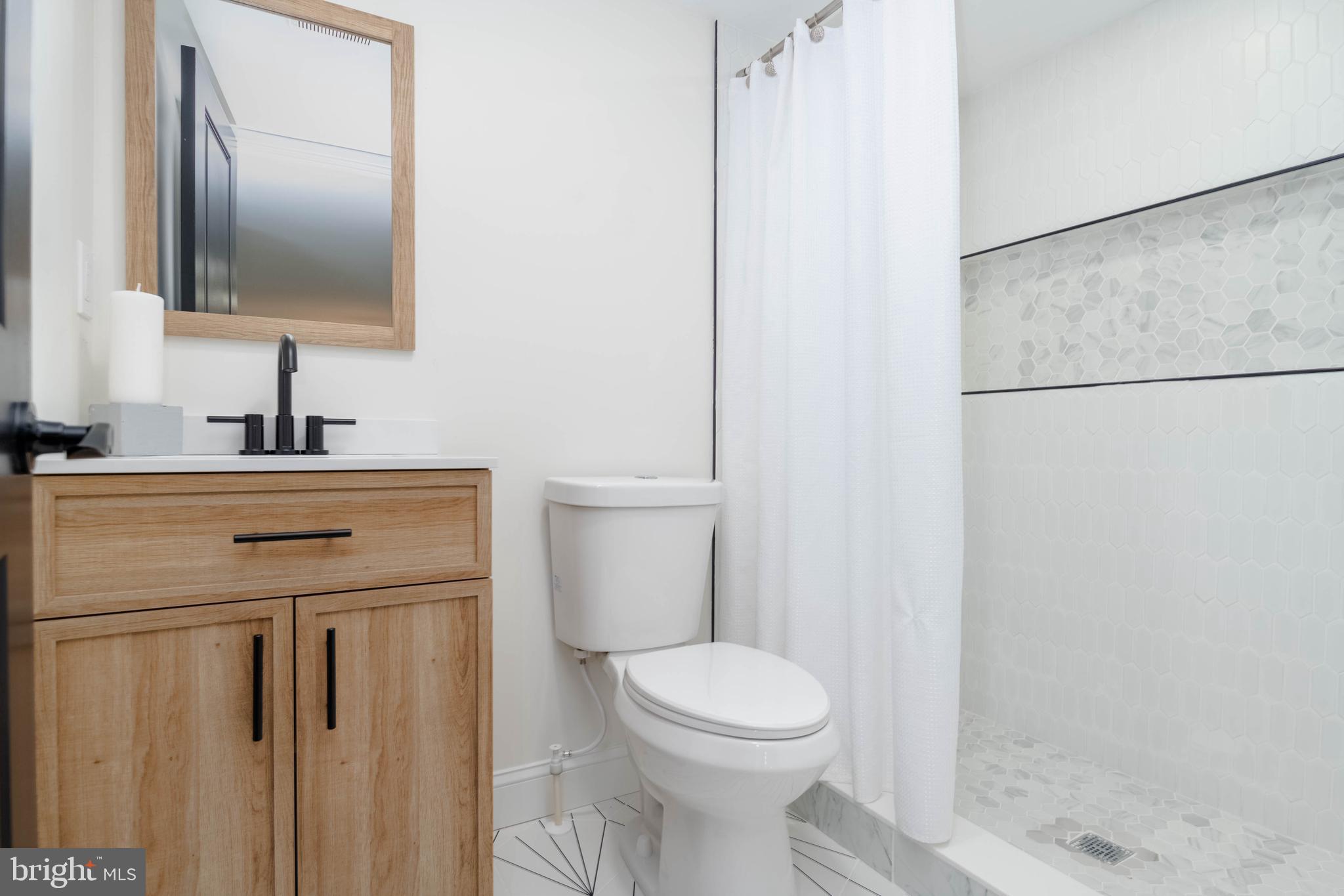 1117 Overbrook Road Baltimore, MD 21239 - Photo 17 of 37 a bathroom with a toilet a sink and a mirror